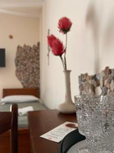a table with a vase with red flowers in it at Sole Mare B&B in Giardini Naxos