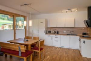a kitchen with white cabinets and a wooden table at mivida - Apartment zum Arber in Hohentauern +3 photos