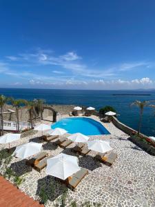 a swimming pool with umbrellas and chairs next to the ocean at Pagoda Lifestyle Hotel in Ischia