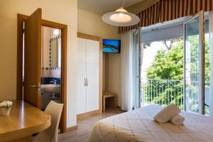 Hotel Sylvia في ليدو دي كامايوري: غرفة نوم بسرير ومكتب ونافذة