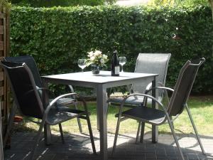 a white table with three chairs and a bottle of wine at Fewo65 Residenz am Strand in Zingst