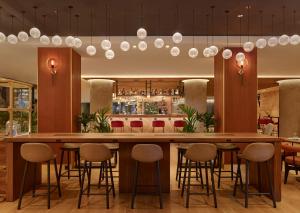 ein Restaurant mit einer Bar mit Hockern drum herum in der Unterkunft Sheraton Amsterdam Airport Hotel and Conference Center in Schiphol