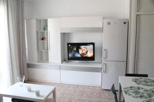 een woonkamer met een tv en een witte koelkast bij Apartamento Carlota beach carihuela in Torremolinos