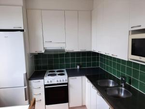 a kitchen with white cabinets and green tiles at 50m2 Cozy Apartment, FREE Parking 20 min to Center in Espoo