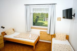um pequeno quarto com 2 camas e uma janela em Pension U Blinků em Dolní Bečva