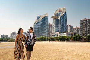 a man and woman standing on the beach with a frisbee at Sheraton Zhanjiang Hotel in Zhanjiang