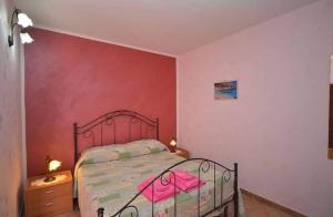 Un dormitorio con una cama y una pared roja. en Casa Sarina, en San Vito lo Capo