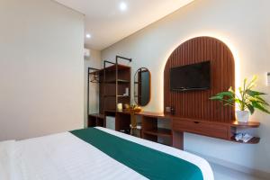 a bedroom with a bed and a tv on a wall at Cove Ransha Stay in Sanur