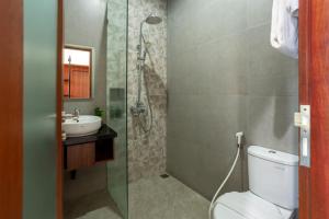 uma casa de banho com um chuveiro, um WC e um lavatório. em Cove Ransha Stay em Sanur