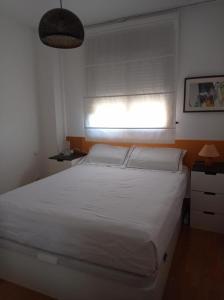 a bedroom with a white bed and a window at APARTAMENTO BARAJAS-IFEMA in Madrid