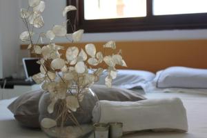 a glass vase with white flowers on a bed at APARTAMENTO BARAJAS-IFEMA in Madrid