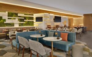 a restaurant with a blue couch and tables and chairs at Sheraton Amsterdam Airport Hotel and Conference Center in Schiphol