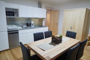eine Küche mit einem Holztisch und eine Küche mit weißen Schränken in der Unterkunft Kovárna Residence in Pec pod Sněžkou