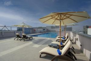 un patio con sillas y sombrillas y una piscina en Jood Hotel Apartments, en Dubái