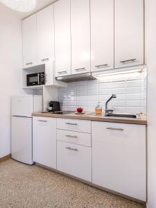 una cocina blanca con armarios blancos y fregadero en Breeze 1BD Apartment by BluPine, en Atenas