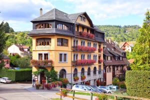 un grand bâtiment jaune avec des boîtes de fleurs dans l'établissement LE CLOS DES SOURCES Hôtel & Spa, à Thannenkirch