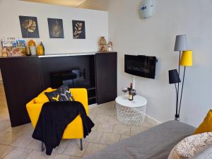 a living room with a yellow chair and a tv at Casa Maria Beatrice in Mühlbach