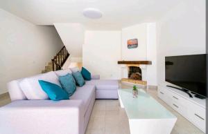 een woonkamer met een witte bank en een open haard bij Marina Holiday House in Quarteira