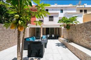 a patio with chairs and palm trees in front of a building at Marina Holiday House in Quarteira