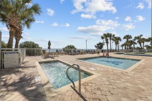 a pool with palm trees and the ocean in the background at Ocean Front 2BR Elegant Condo in Atlantica Resort in Myrtle Beach