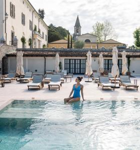 Una donna seduta in piscina in un hotel di QC Termegarda Spa & Golf Resort a Calvagese della Riviera