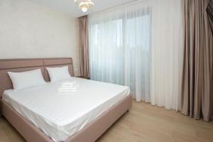 a bedroom with a bed with white sheets and a window at Lake On Apartments in Mamaia