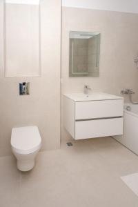 a white bathroom with a toilet and a sink at Lake On Apartments in Mamaia