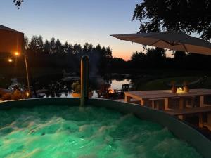 a hot tub with water in it with a table and an umbrella at Het Blauwe Huysch in Putten