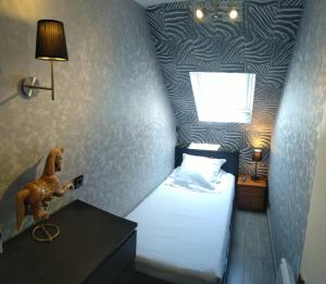 a small bedroom with a bed with a horse on the wall at L'échappée belle in Touques