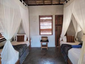 sypialnia z 2 łóżkami z zasłonami i oknem w obiekcie Kampung Kakak w Nembrali