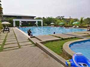 una gran piscina con gente sentada a su alrededor en Cosy Spacious Homestay in Central Batu Pahat with Wifi & GENTING Clubhouse, en Kampong Sri Gading
