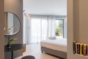 a bedroom with a bed and a mirror and a window at Villa Artemis in Ágios Stéfanos