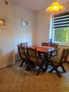 a dining room with a wooden table and chairs at Pokoje Gościnne LENAILI in Jarosławiec