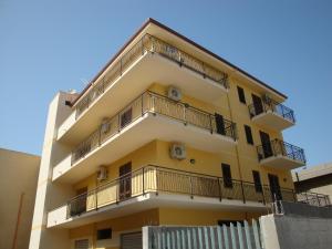 a tall yellow building with balconies on it at Appartamenti Campo in Trappeto