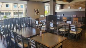 a dining room with wooden tables and chairs at Hotel Route-Inn Court Kofu Isawa in Fuefuki