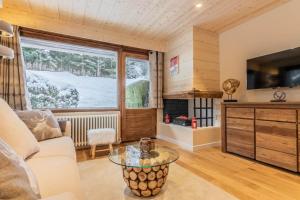 ein Wohnzimmer mit einem Sofa, einem Tisch und einem Fenster in der Unterkunft Apartment Les Cerfs in Megève