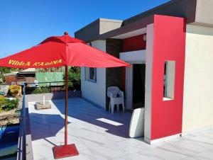 a red umbrella on a patio in front of a house at Villa de vacances privative in Toamasina