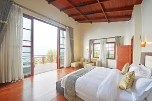 a bedroom with a large bed and a balcony at Gorilla Heights Lodge in Kisoro