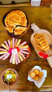 uma mesa de madeira com tartes e outros alimentos em Fazenda Quinta da Esperança- Pousada e Lazer em Tiradentes