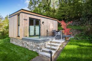a small wooden cabin with a stone wall at Comfy Lake District Cabins - Winster, Bowness-on-Windermere in Winster