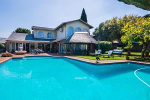 a swimming pool in front of a house at Golfer's Lodge in Edenvale