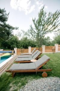 a row of chaise lounges on the grass near a pool at Das Holzhaus in Sadu