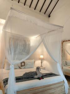 - un lit à baldaquin blanc avec un oiseau rembourré dans l'établissement Candra Surf Homestay, à Canggu