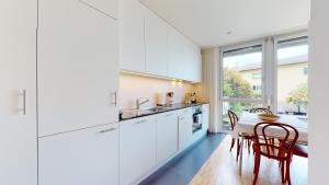 a kitchen with white cabinets and a table and chairs at Bright flat overlooking Lake Geneva in Montreux