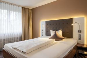 Schlafzimmer mit einem großen weißen Bett und einem Fenster in der Unterkunft Hotel Fuchsen in Kirchheim unter Teck