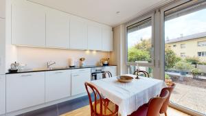 een keuken met witte kasten en een tafel met stoelen bij Bright flat overlooking Lake Geneva in Montreux