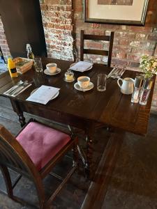 una mesa de madera con tazas y platillos. en The Red Lion Charing Heath en Charing