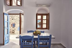 a dining room with a table and blue chairs at Amphitheater Cave Houses in Fira