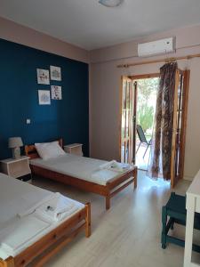 a bedroom with two beds and a blue wall at Filoxenia Apartments in Rizá