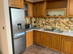 a kitchen with wooden cabinets and a stainless steel refrigerator at Апартамент за гости ТРАПЕЗИЦА МАК in Veliko Tŭrnovo
